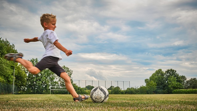 Chlapec kopající do míče na fotbalovém hřišti